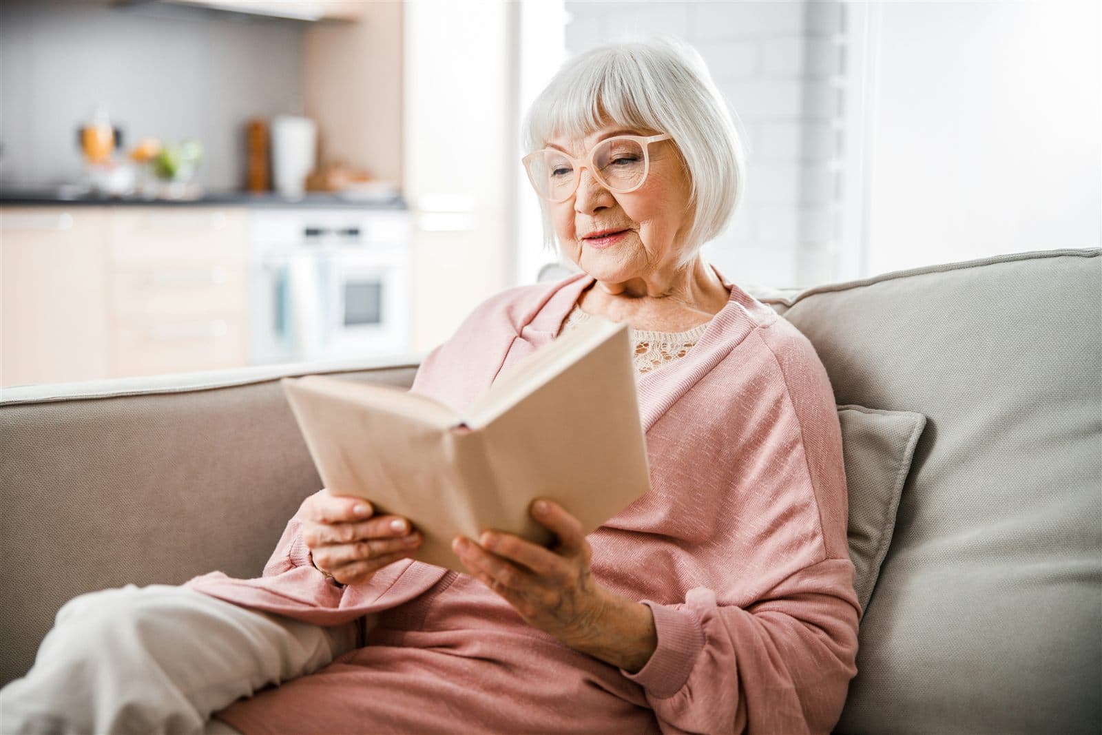An older woman relaxing on a sofa, enjoying a book